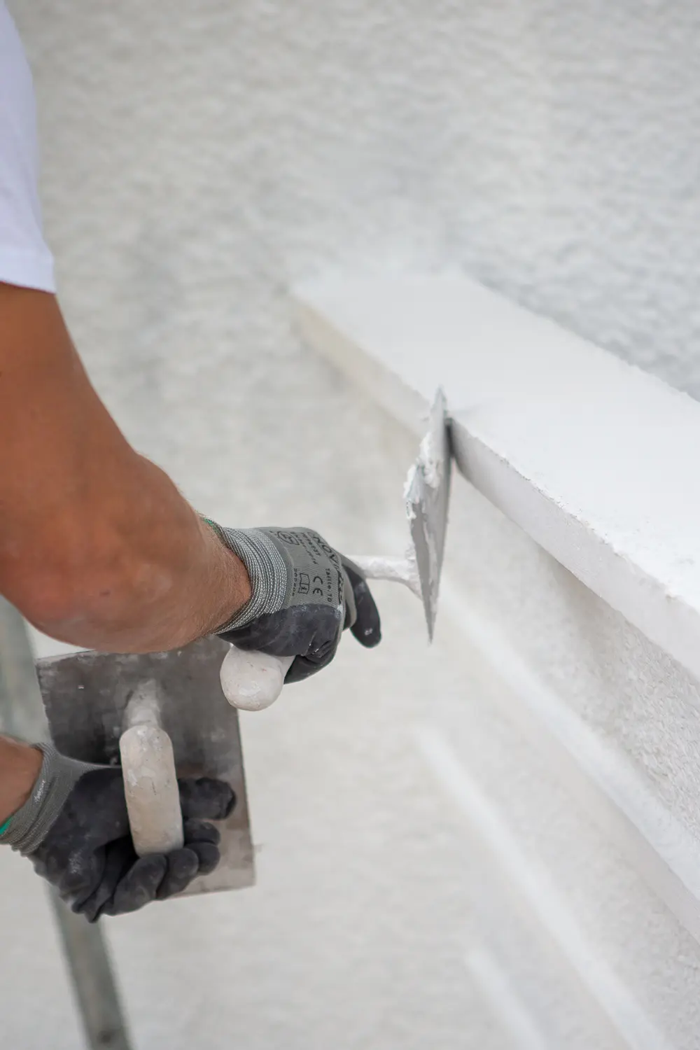 Une main appliquant un produit sur un mur avec précaution et expertise.