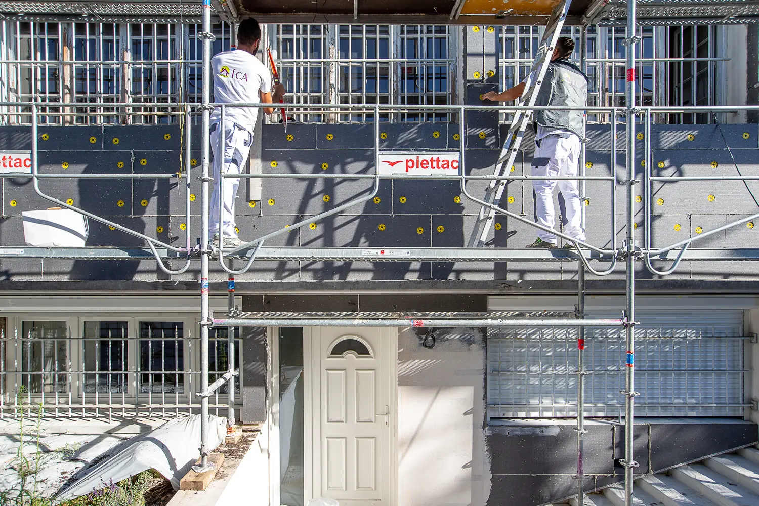 Deux personnes en train de rénover la façade d'une maison avec dévouement et habileté.
