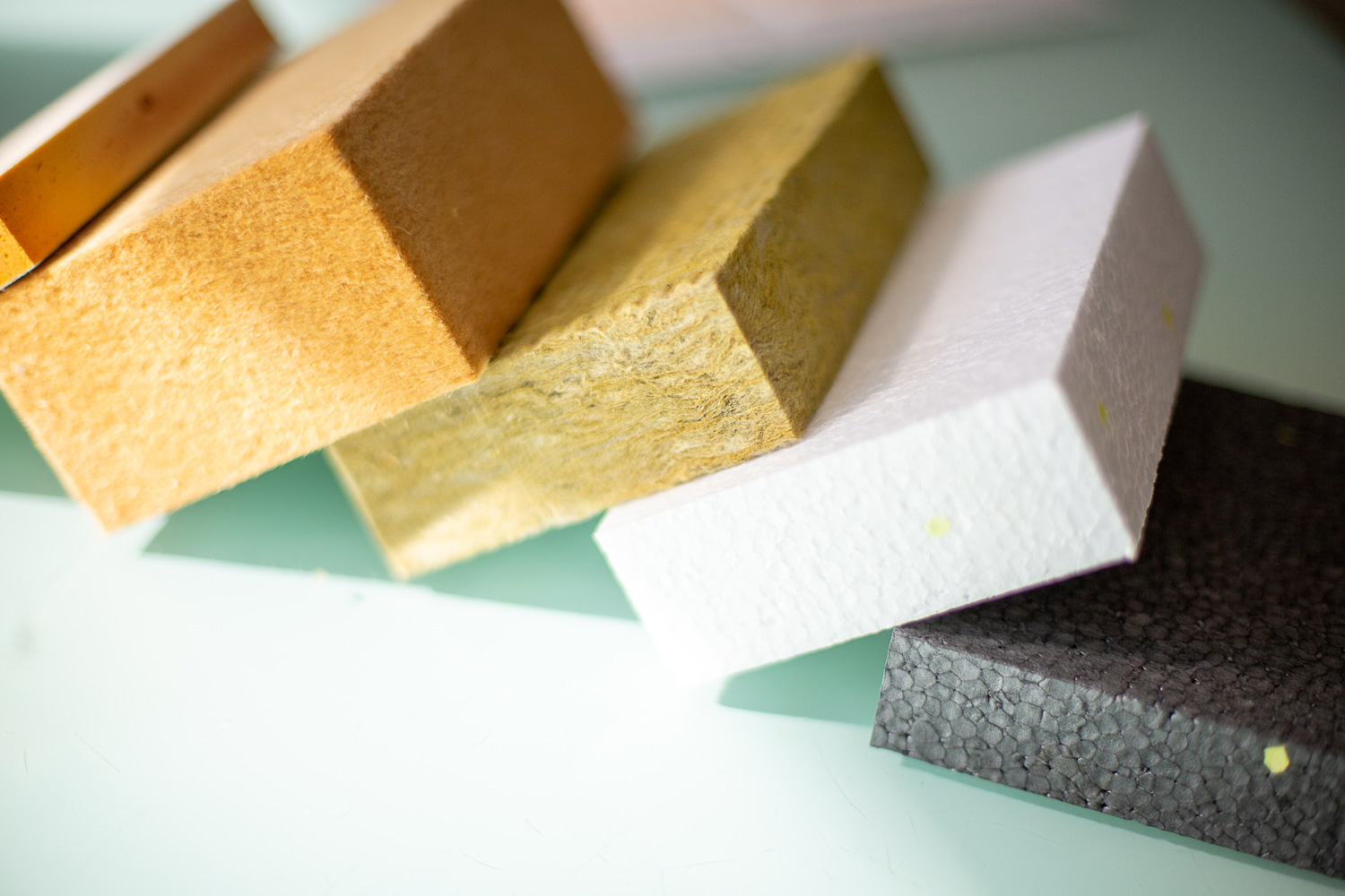 Des échantillons d'isolant pour mur disposés sur une surface, représentant différentes options de matériaux isolants pour les murs.